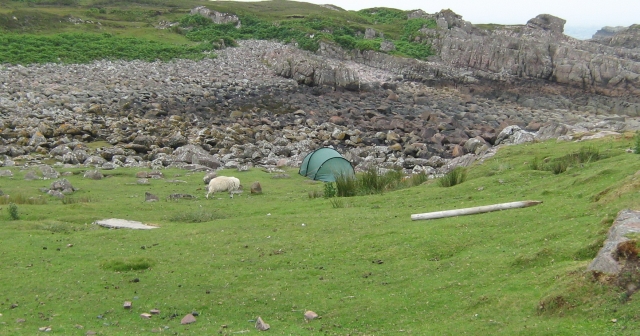 a tent amongst rocks and a patch of grass near cove in scotland